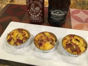 Three barbecue breakfast cupcakes on serving platter with sriracha and barbecue sauce