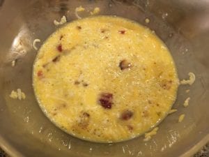 Chopped bacon and shredded cheese added to egg mixture