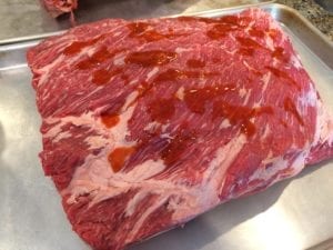 Sprinkling Louisiana hot sauce onto short ribs