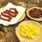 Cooked bacon slices, scrambled eggs, and apple fritter