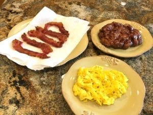 Cooked bacon slices, scrambled eggs, and apple fritter