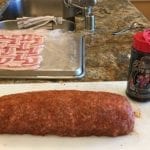 Applying barbecue rub to sausage log