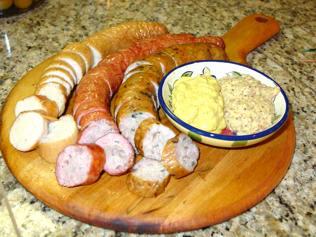 Gourmet sausages served on a cutting board with two mustards