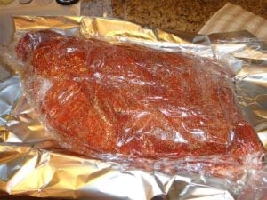 Rubbed brisket wrapped in plastic wrap and foil
