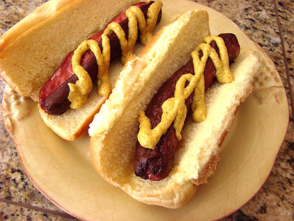 Two hot dogs with buns and spicy mustard