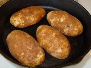 Buttered potatoes face down in iron skillet