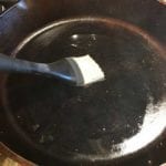 Brushing 1 teaspoon of bacon fat in skillet