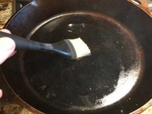 Brushing 1 teaspoon of bacon fat in skillet