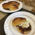 Pork butt with coleslaw on hoecakes with extra cakes in background