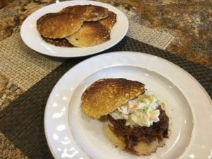 Pork butt with coleslaw on hoecakes with extra cakes in background