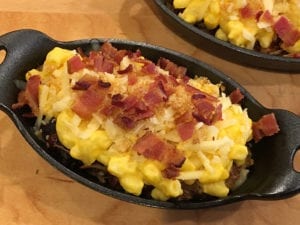 Dish topped with shredded Gouda, bread crumbs and bacon bits