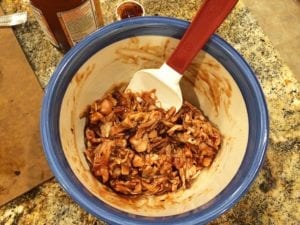 Mixing chicken with warm barbecue sauce