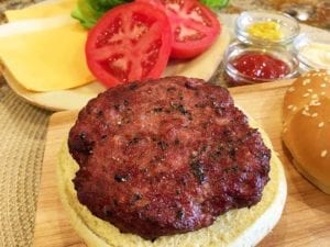 Close-up of bacon/beef burger on a bun with condiments