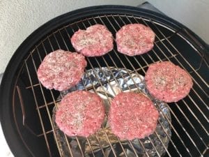 Uncooked patties on the top cooking grate