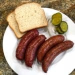Plated sausages with white bread, onions and pickles