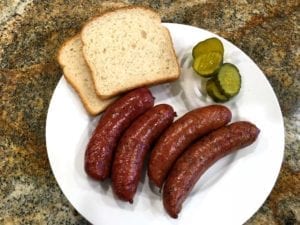 Plated sausages with white bread, onions and pickles