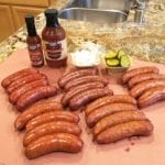 Smoked Southside Market sausages with BBQ sauce, hot sauce, onions and pickles