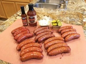 Smoked Southside Market sausages with BBQ sauce, hot sauce, onions and pickles