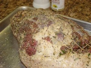 Close-up of leg of lamb sprinkled with kosher salt and lemon pepper
