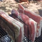 Three pieces of cured pork belly in a rib rack
