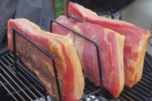 Three pieces of cured pork belly smoking in the Weber Bullet