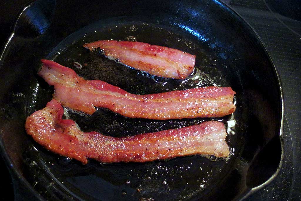 Frying homemade bacon in a cast iron skillet