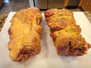Spreading mustard over the surface of the pork butts