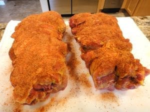 Applying a generous amount of rub to the pork butts