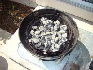 Lit coals spread over unlit briquettes