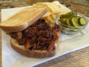 Rib sandwich served with potato chips and pickles