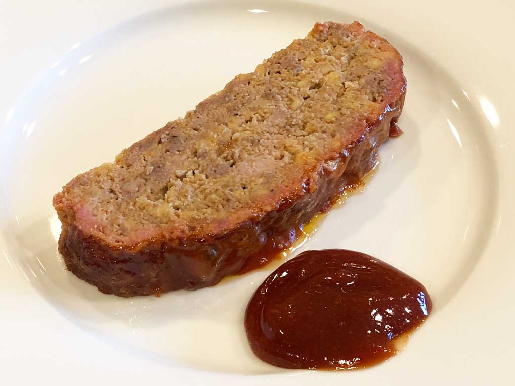 Slice of meatloaf with sauce on the side
