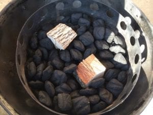 Smoke wood on top of unlit charcoal briquets