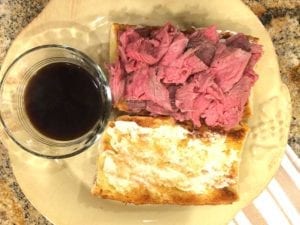 Sliced rib roast on toasted roll with garlic butter, creamy horseradish and au jus