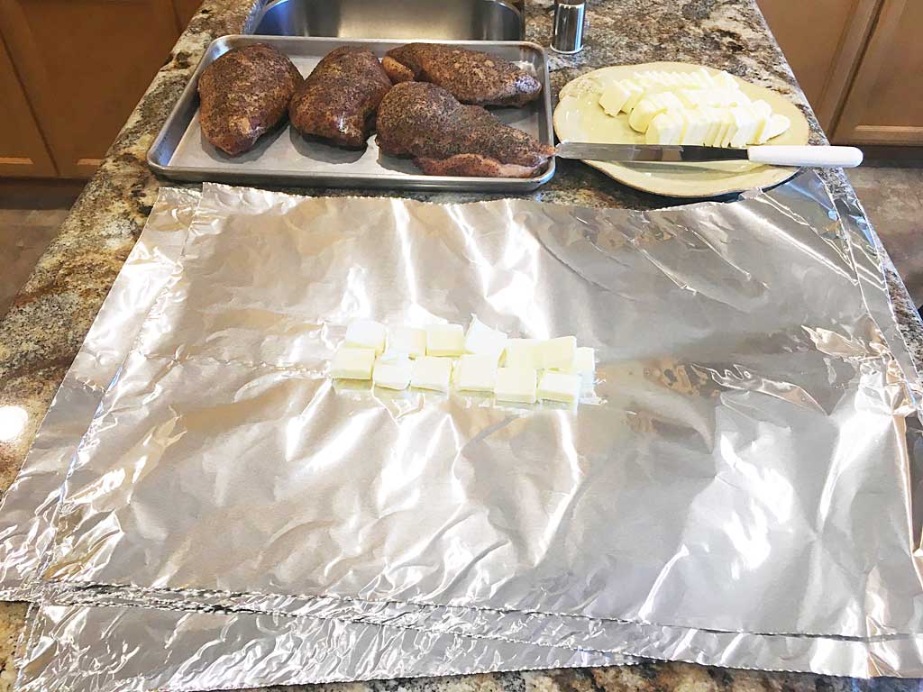 One stick's worth of butter pats arranged on two sheets of aluminum foil