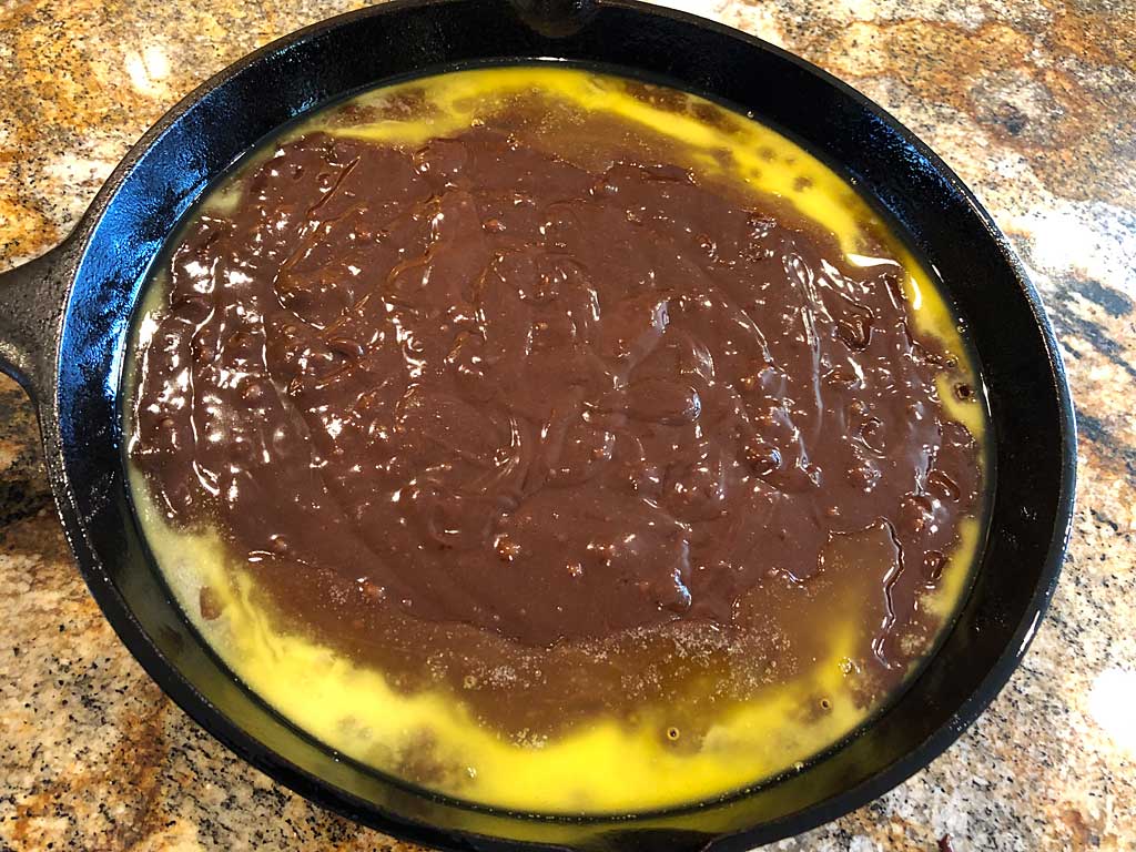 Brownie batter with melted butter in prepared cast iron skillet