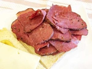 Pastrami on rustic white bread with swiss cheese and brown mustard