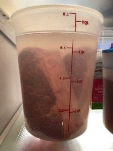 Soaking corned beef in water to reduce saltiness