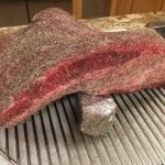 Brisket draped over foil-wrapped smoke wood chunk