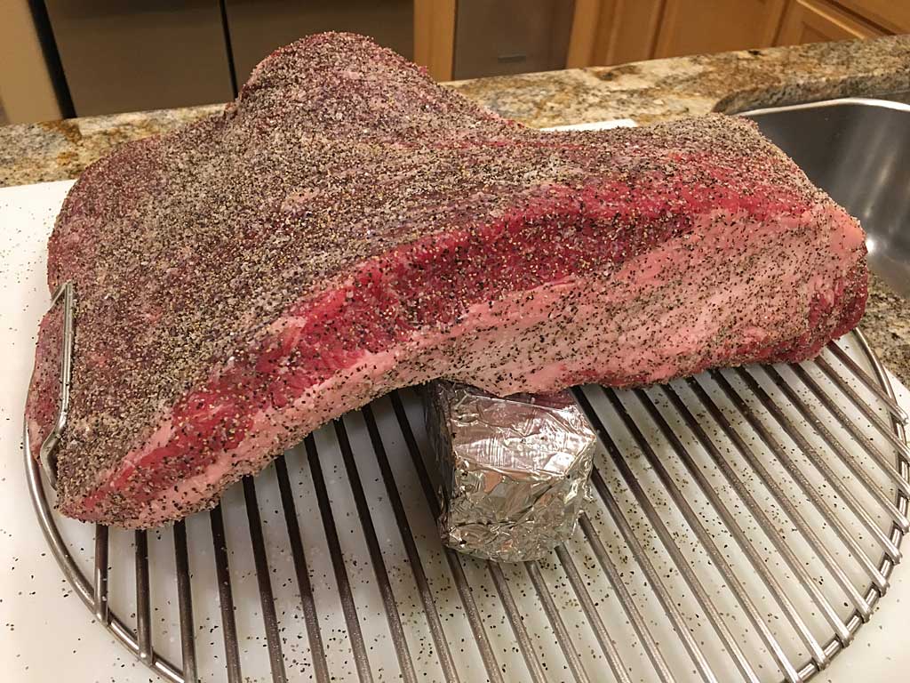 Brisket draped over foil-wrapped smoke wood chunk