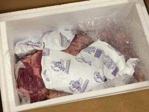 Brisket inside Styrofoam cooler with frozen ice gel packs