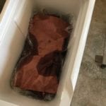 Pink butcher paper wrapped brisket rests in dry cooler