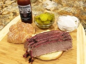 Brisket sandwich with pickles, onions, and sauce on the side