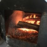 Post oak burning in a pit's firebox