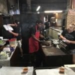 Staff cutting meat and filling orders behind the counter