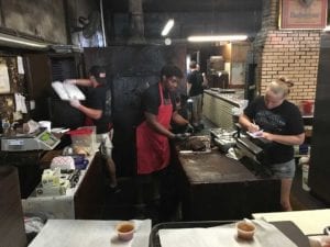 Staff cutting meat and filling orders behind the counter
