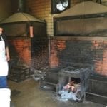 Employee standing next to dedicated sausage pit in backroom