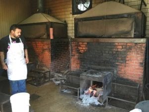 Employee standing next to dedicated sausage pit in backroom