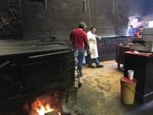Open fire at end of pit and sawdust covered floors