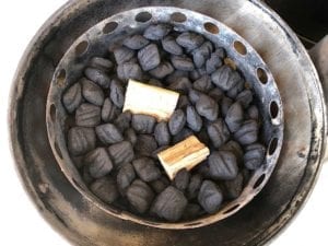 Wood chunks nestled into unlit charcoal