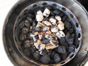 Lit charcoal spread over unlit briquettes